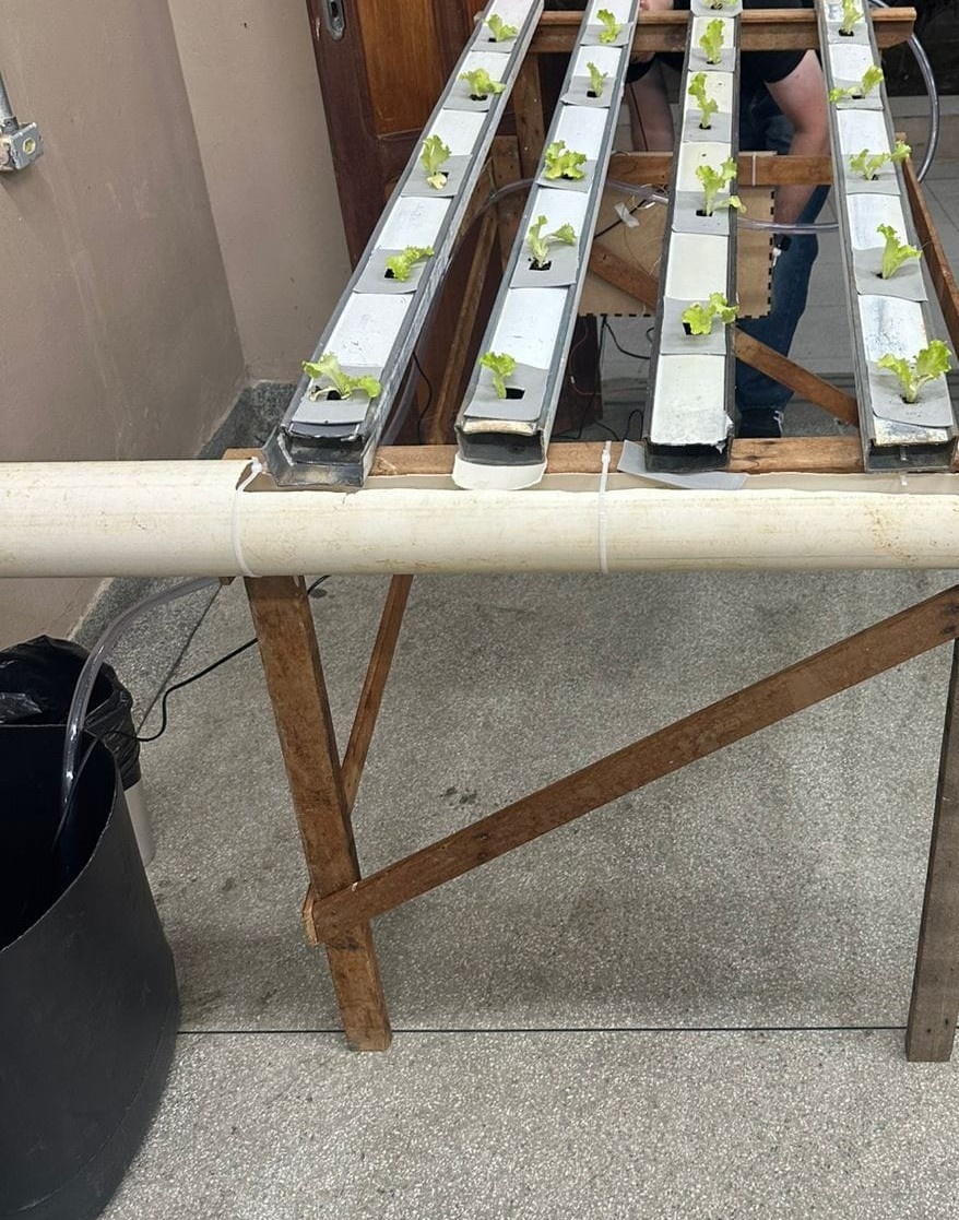 Com isso, conecte os registros e tês nas aberturas dos perfis intercalando uma pequena porção de mangueira cristal entre eles. Posicione também o cano de PVC na parte inferior da estrutura.
OBS: a estrutura da hidroponia deve ser feito de forma inclinada para melhor circulação da corrente de água.