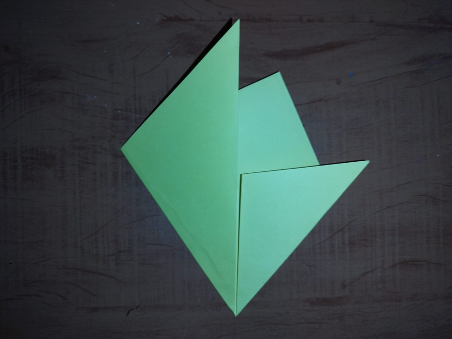 Agora nós usaremos a ponta esquerda do triângulo, puxando-a para cima indo para direita, até ela se alinhar com nossa dobra anterior, como segue na imagem. Marque bem!