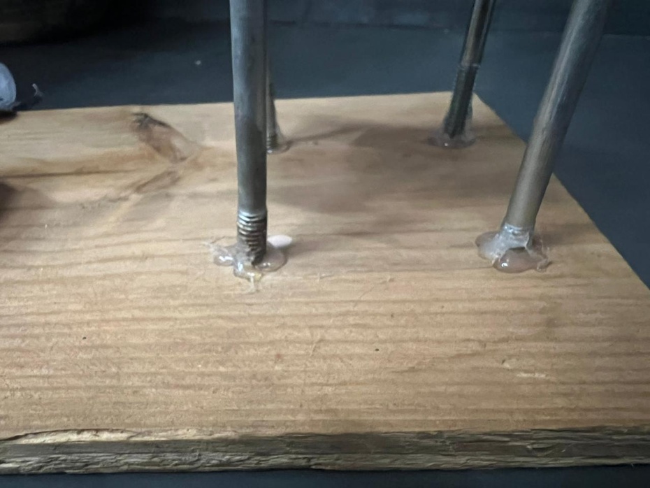 Faça 4 furos do tamanho da lata na madeira. Fixe os quatro parafusos/pregos, se precisar, use cola quente.