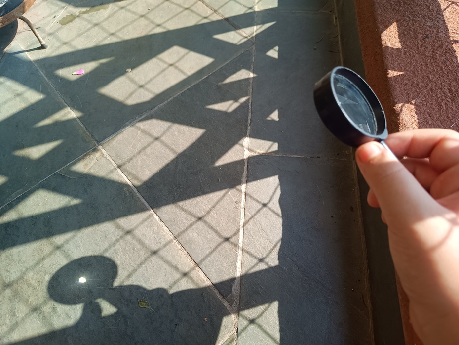 Coloque a lupa ao Sol e distancie-a ou aproxime-a do chão até formar um pequeno ponto luminoso no chão, em seguida, meça a distância desse ponto à lupa.