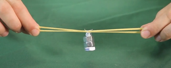 Usando a linha de costura, prenda dois elásticos no parafuso. Com a linha amarre o meio dos elásticos ao lado oposto à cabeça do parafuso.