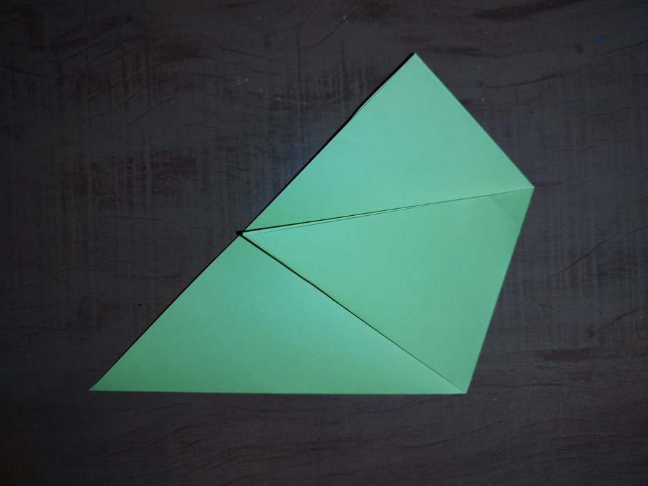 Agora você desdobra sua dobra recém feita, e veja que tem uma marca na horizontal, e puxe a ponta do seu triângulo direita até a extremidade esquerda da marca na horizontal. Marque bem!
