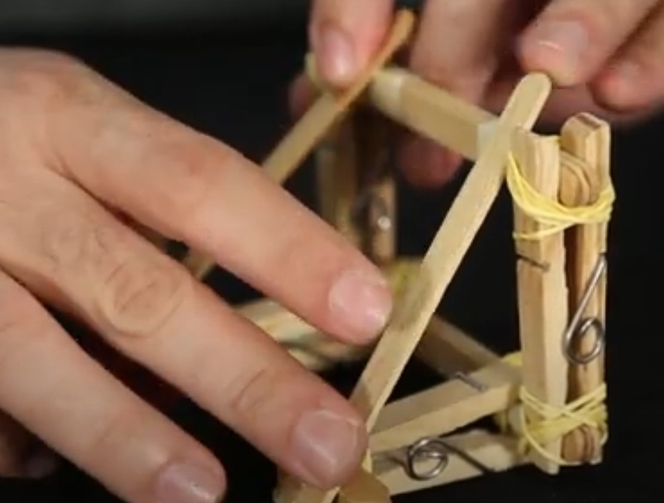 Deixe a estrutura em pé (retângulo maior em pé e base no chão) coloque um palito de sorvete ligando um canto de cima do retângulo maior com um canto da base (o lado mais próximo). Faça o mesmo com o outro lado e outro palito.