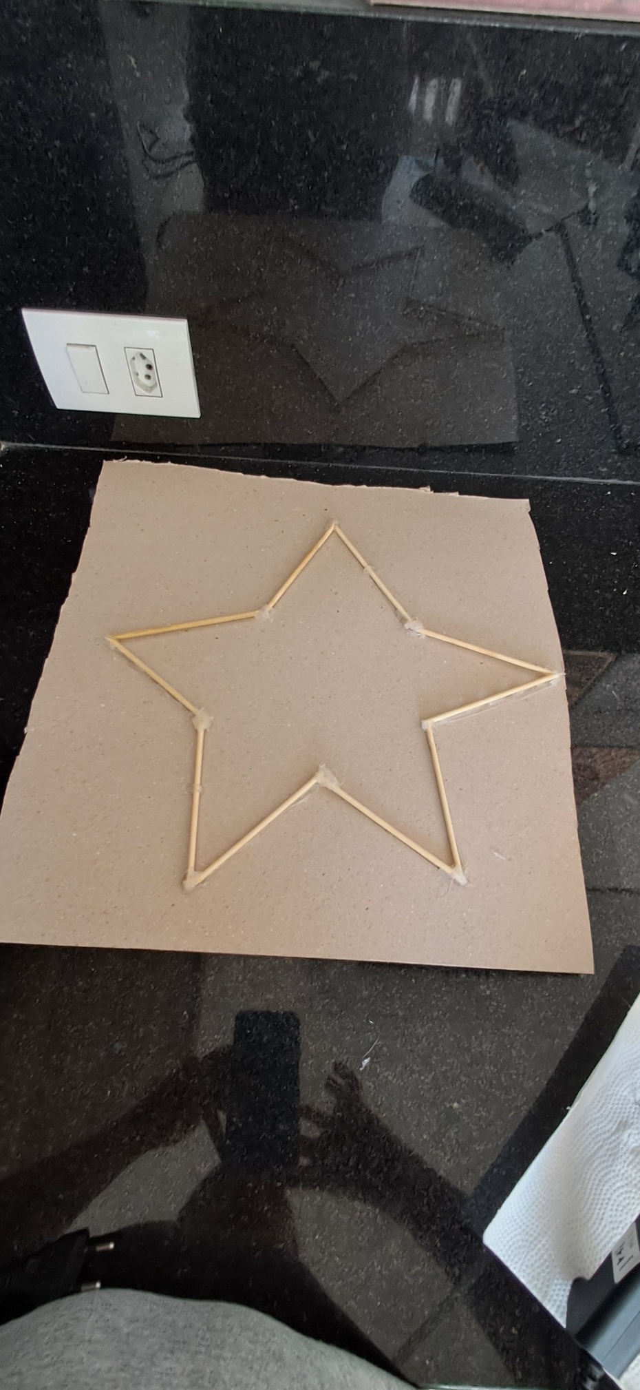 1- Pegue a estrela de palitos e o papel Paraná.
2- Posicione a estrela em um dos cantos do papel 
3- Marque o formato da estrela
4- Corte com a tesoura ou estilete.
5- cole atrás da estrela