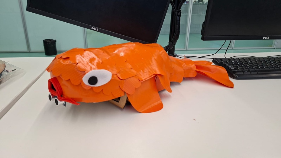 Agora chegou a parte onde todos esperavam!!! A sessão artística:D
Nessa etapa, preencha o seu peixe com o material que você preferir, no nosso caso, utilizamos espuma e a ajustamos na forma do MDF para ficar bonito. Esta etapa será fundamental para tanto, a sustentação/suporte do peixe, quando o aprimoramento da elegância visual.
Depois estilize e cubra o peixe com o material de sua preferência, ou que você tiver em casa (fita crepe, lona, etc). É possível reutilizar aquele material que seria descartado. Tenha em mente que este material não pode ser muito comprido porque se não vai enroscar na roda ou arrastar no chão. 
Por fim, caso decida customizar ainda mais o seu peixe, você pode acrescentar detalhes extras como olhos, nadadeiras, escamas, caudas, entre outros cosméticos para aprimorar o nível de detalhes e o realismo de seu mascote.