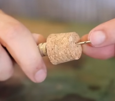 Perfure o centro da rolha com o bico da bomba de ar até que o furo do bico atravesse a rolha e fique totalmente exposto do outro lado.