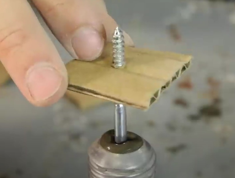 Insira, com cuidado, o lado da cabeça do parafuso até chegar no papelão.