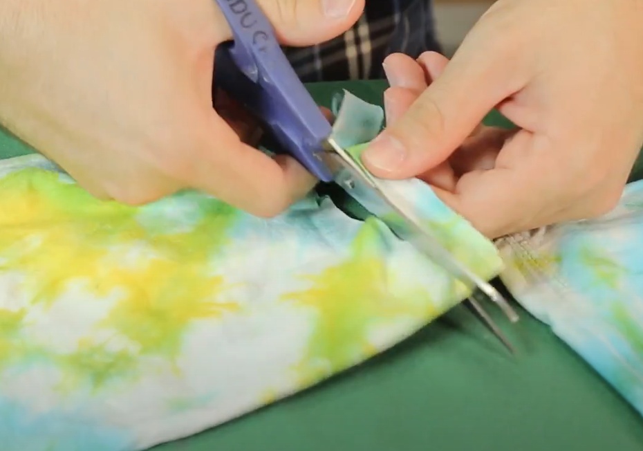 Usando as mangas da camiseta que cortamos, corte duas tiras de, aproximadamente, 1,5cm de largura.  Faça um corte no meio de cada tira.