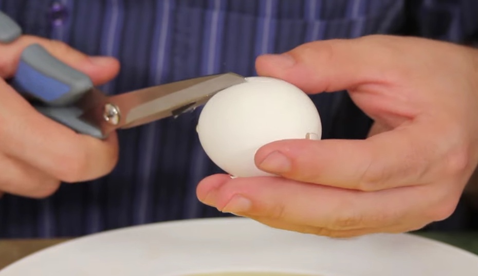 Agora que os ovos estão sem clara e gema, utilize uma tesoura para cortar de cima para baixo, a fim de conseguir uma concha. Foram indicados 2 ovos pois uma das metades fica um pouco destruída.