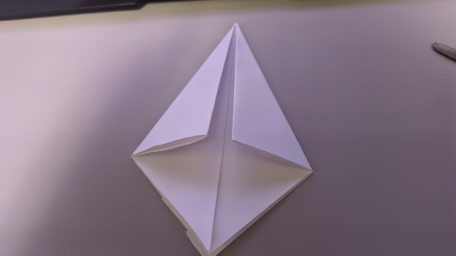 Pegue a outra folha e dobre as pontas do meio (nem a de cima nem a de baixo) e leve elas até o centro do papel