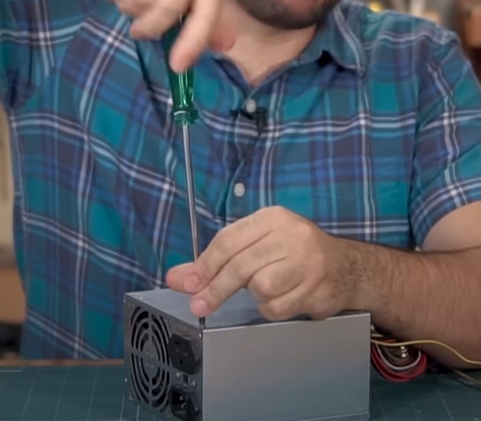 Utilizando a chave de fenda Philips, desparafuse, abra e retire a tampa da fonte.