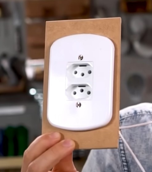 Utilize a serra tico-tico para cortar a tampa da caixa apenas o suficiente para encaixar e parafusar a tomada dupla. Utilize EPI. 