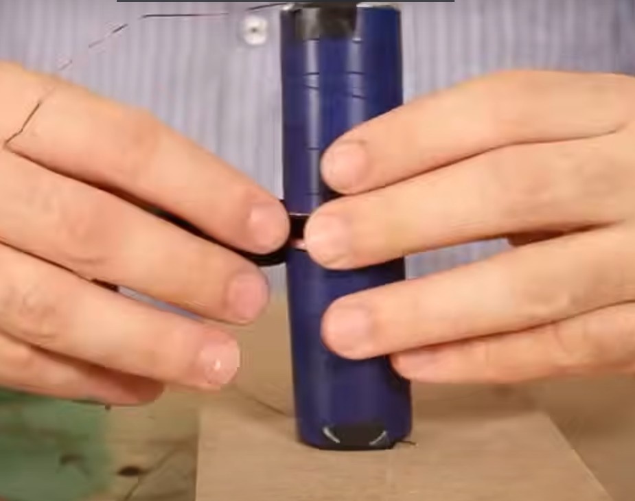 Coloque a outra ponta do fio de cobre enrolado no polo negativo que ficou livre das pilhas. Passe fita isolante para que ele fique preso.