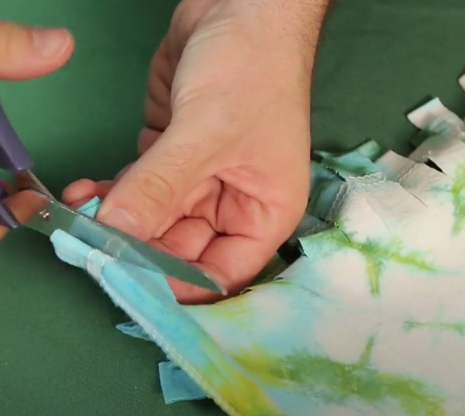 Na parte da cintura da camiseta faça cortes em direção a gola da camiseta, cortando em tiras de aproximadamente 4cm de comprimento e 1cm de largura. Você deve cortar, ao mesmo tempo, o lado da frente e o lado de trás da camiseta.