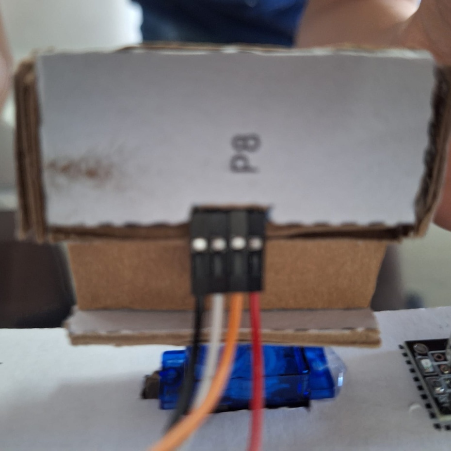 Conecte o pino Echo do sensor de distância no pino 9, o Trigger no 8, o pino 5V na trilha positiva da protoboard e o GND na trilha negativa. PASSE OS FIOS PELO BURACO MAIS PRÓXIMO NO CANTO DIREITO DA BASE DO ROBÔ.