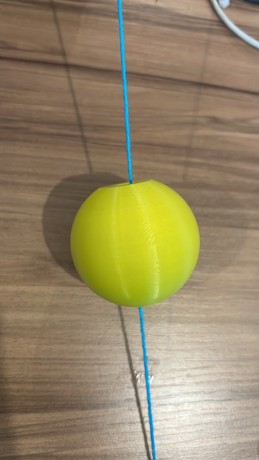 Enfie uma das pontas no buraco que atravessa a bola e puxe até o fio sair do outro lado. Se estiver difícil, use um palito ou agulha pra empurrar.