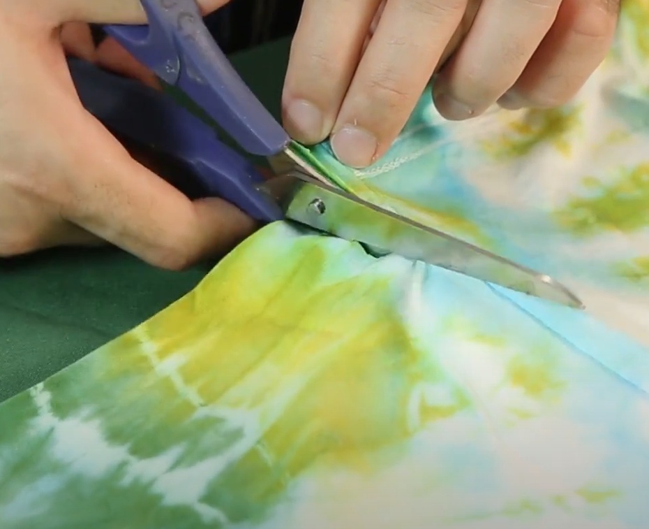 Para fazer as alças da sacola, precisamos cortar as mangas da camiseta. Use a tesoura para cortar as mangas, mas preserve a costura da cava! Assim sua sacola terá mais resistência.