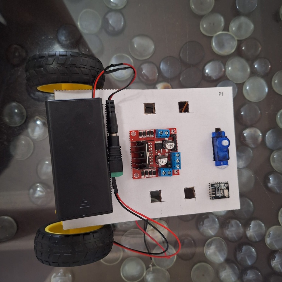 Vire o Rolinho de barriga para baixo. Cole na parte de cima nos espaços indicados o suporte para bateria 18650 SEM AS BATERIAS, o driver L298N e o módulo receptor infravermelho KY - 022. (Na imagem, é possível observar junto ao suporte para bateria um conector P4 macho e fêmea. Apenas utilizei estas peças por uma questão de versatilidade com outros projetos.)