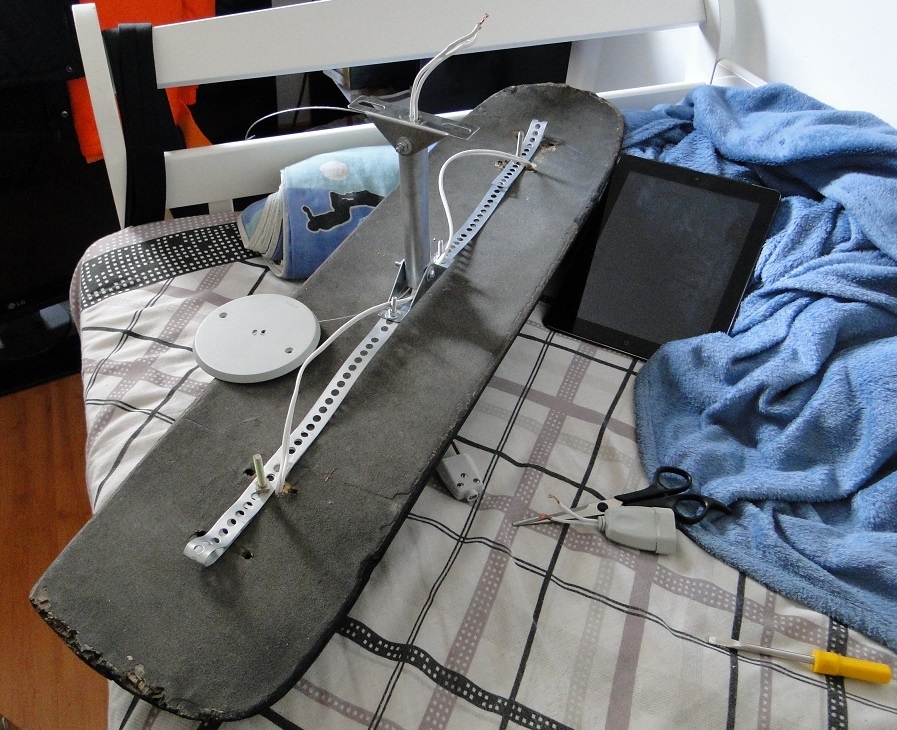 O triângulo de ferro de baixo, você conecta com parafusos bem no meio do shape, depois de travar os parafusos, levante para ver se ficou equilibrado, se não ficar mude os furos da fita metálica perfurada ou adicione pesos no lado que estiver mais leve. O triângulo de ferro de cima, você instala no teto após fazer as ligações elétricas com a rede elétrica.