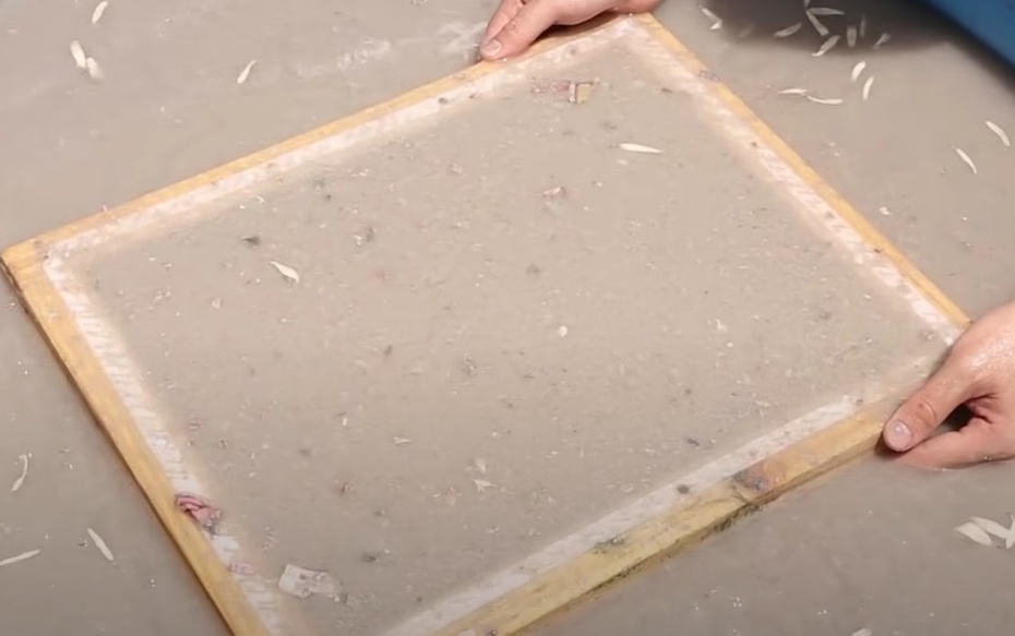 Coloque a tela dentro do recipiente, movimente um pouco de um lado para o outro e levante a tela devagar. Repare que será criada uma camada de papel na tela.