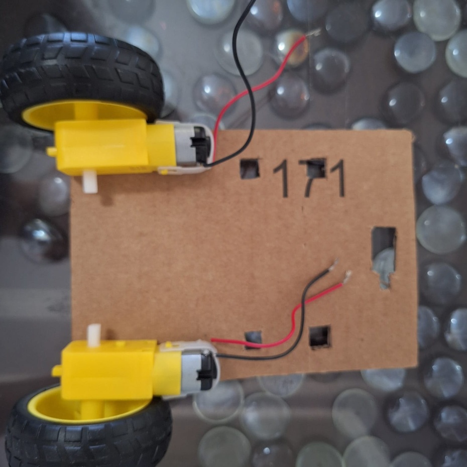 Posicione a maior peça de papelão (a base do corpo do Rolinho) embaixo dos motores com a face branca virada para baixo. Depois disso, fixe os motores nesta posição com cola quente ou fita dupla face.